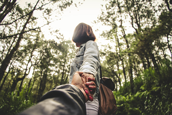 Photo d'une femme tenant la main de quelqu'un dans la forêt